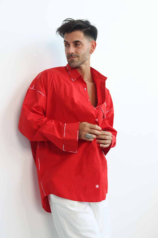 A person wearing a red long-sleeve shirt with a classic collar and black hand-painted details, paired with white pants.