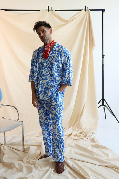 a coral print linen set with a button-down shirt and 3/4 sleeves, paired with matching relaxed pants with an elastic waistband and drawstring.
