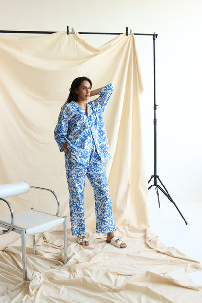 a coral print linen set with a button-down shirt and 3/4 sleeves, paired with matching relaxed pants with an elastic waistband and drawstring.