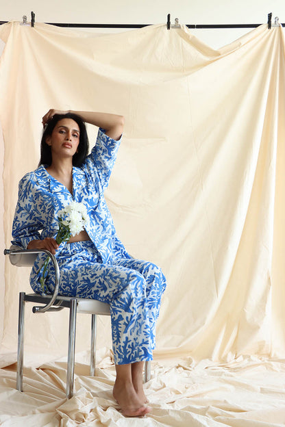 a coral print linen set with a button-down shirt and 3/4 sleeves, paired with matching relaxed pants with an elastic waistband and drawstring.