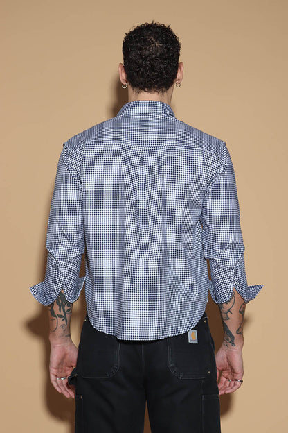 The front button down low crop shirt with a shirt collar and front button closure might seem like your run of the mill shirt. However the shirt can be styled partially sleeved or completely sleeveless with detachable sleeves that can be snapped on and off in parts or completely.  The monochrome check shirt is the perfect cropped moment that lets you style it in more ways than one. Go for the full sleeves, cold shoulder on either or both arms or completely sleeveless - the possibilities are endless.