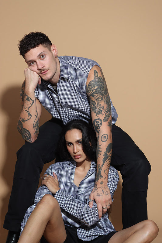 The front button down low crop shirt with a shirt collar and front button closure might seem like your run of the mill shirt. However the shirt can be styled partially sleeved or completely sleeveless with detachable sleeves that can be snapped on and off in parts or completely.  The monochrome check shirt is the perfect cropped moment that lets you style it in more ways than one. Go for the full sleeves, cold shoulder on either or both arms or completely sleeveless - the possibilities are endless.