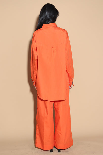 Orange set with a button up shirt with contrasting button stitches and wide leg pants with elastic that can be adjusted accordingly. The Pieces are designed to be oversized and styled casually.  Along with an easy and relaxed fit shirt, the separates can be styled together for a statement.