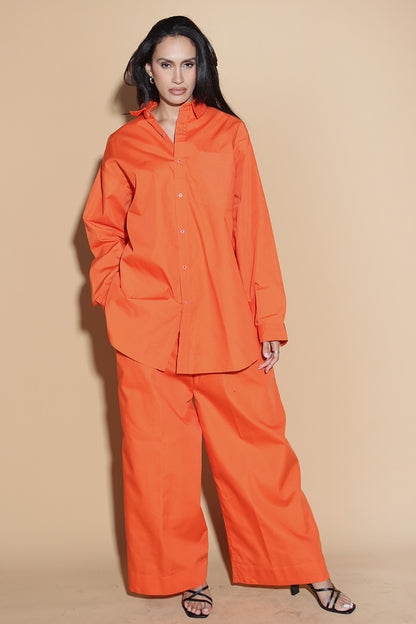 Orange set with a button up shirt with contrasting button stitches and wide leg pants with elastic that can be adjusted accordingly. The Pieces are designed to be oversized and styled casually.  Along with an easy and relaxed fit shirt, the separates can be styled together for a statement.