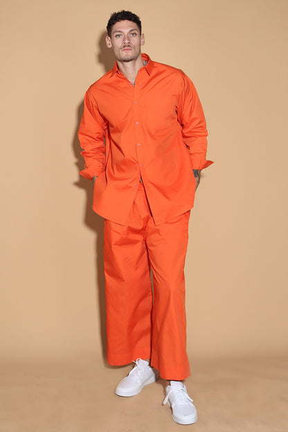 Orange set with a button up shirt with contrasting button stitches and wide leg pants with elastic that can be adjusted accordingly. The Pieces are designed to be oversized and styled casually.  Along with an easy and relaxed fit shirt, the separates can be styled together for a statement.