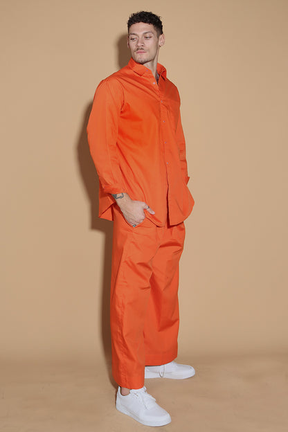 Orange set with a button up shirt with contrasting button stitches and wide leg pants with elastic that can be adjusted accordingly. The Pieces are designed to be oversized and styled casually.  Along with an easy and relaxed fit shirt, the separates can be styled together for a statement.