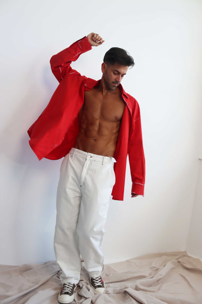 A person wearing a red long-sleeve shirt with a classic collar and black hand-painted details, paired with white pants.