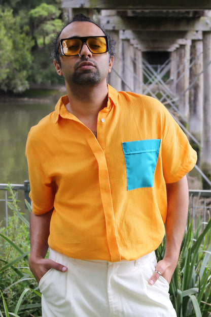 An easy breathable cotton shirt is a perfect summer staple. The shirt in a woven cotton in a striking yellow turns heads for all the right reasons. With a front short and dip hem, the shirt has an accent teal pocket that gives it extra dimension. Short sleeves and a collared neckline in a relaxed cotton are all you need this season for an easy breezy look. 